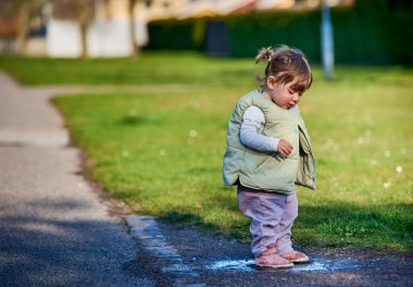 Güneşli bir bahar gününde çamurlu bir su birikintisine atlayan örgülü küçük, yaramaz kız çocuğu. Alçak 2 yaşında bir kız, çimlerin yanındaki küçük bir su yatağında zıplıyor. Çocukların keşfi ve özgürlük kavramı