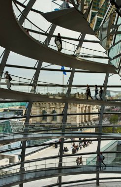 Berlin, Almanya 22 Nisan 2022 - Berlin 'deki Reichstag binasının modern camlı kubbesinde yürüyen insanlar. İnsanlar güneşin altında otururken Alman Reichstag 'ının yuvarlak modern kubbesinin içindeki spiral rampa.