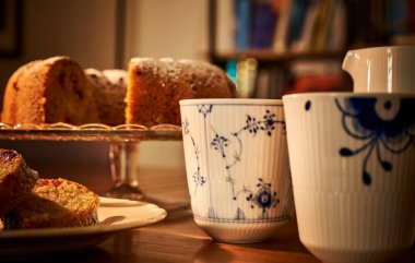 Lüks, eski moda kahve kupası ve romantik bir ortamda dilimlenmiş GF çöreği. Dilimlenmiş donut ve lüks bir fincan sıcak buharlı çay ile sıcak bir ortam konsepti taşır.