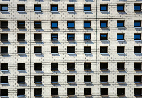 Sharing accommodation in crowded space shows a modern difficult cohabitation or coexistence in capital cities with pattern of little adjacent windows on modern facade. Living space issue in a big city - Berlin, Germany
