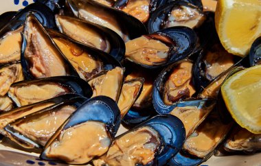 Koyu kabuklu parlak midyeler canlı portakal eti ve sulu limon dilimleri tazeliği, kıyı mutfağını ve basit, doğal deniz ürünleri sunumunun güzelliğini çağrıştırıyor.