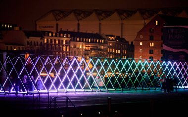 Kopenhag, Danimarka 21 Şubat 2024 - Gece Ofelia Plads: Aydınlatılmış binalara karşı parıldayan üçgen ışık tesisi