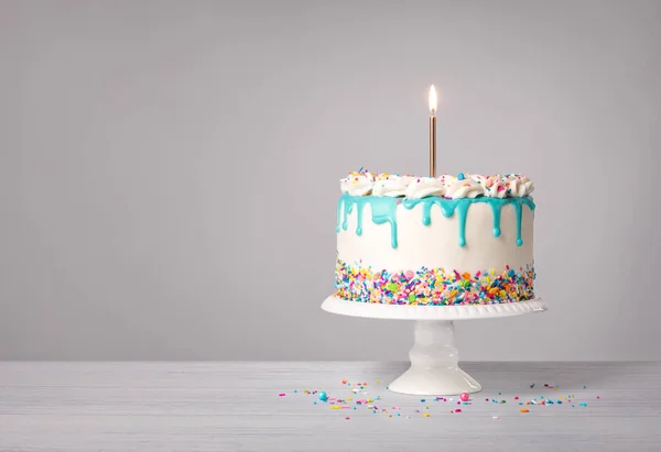 Waniliowy Tort Urodzinowy Ciemnoniebieskim Kroplówką Ganache Zapaloną Złotą Świecą Kolorowymi — Zdjęcie stockowe