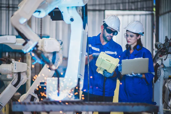 İki mühendis çelik fabrikasında çelik kaynak yapmak için bilgisayar kontrolörü Robotik kol kullanıyor. Otomatik üretim teknolojisi için endüstriyel robot programlama yazılımı