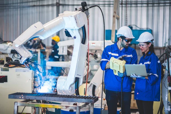 stock image Two engineers mechanic using computer controller Robotic arm for welding steel in steel factory workshop. Industry robot programming software for automated manufacturing technology