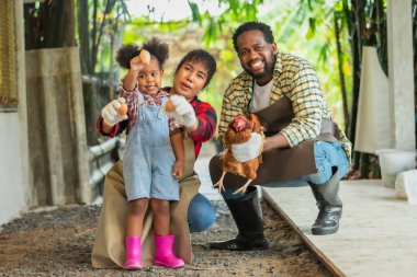 Afrikalı karı koca portresi çocuklara çiftlikte tavuk yetiştirmeyi öğretiyor.
