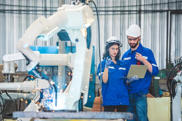 Engineers team mechanic using computer controller Robotic arm for welding steel in steel factory workshop. Industry robot programming software for automated manufacturing technology