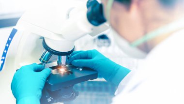 Tıbbi araştırma laboratuvarında ya da bilim laboratuarında mikroskopla bilim insanlarının ellerini kapat. 