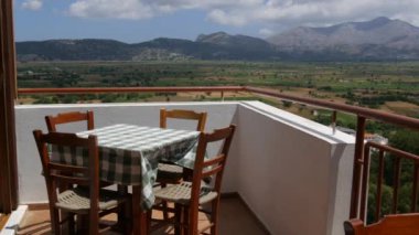 Yunanistan 'ın Girit adasının en önemli yerlerinden biri olan Lassithi Platosu' nun muhteşem doğa manzarası. Girit dağlarıyla çevrili bir restoranın terasında masa ve sandalyeler..