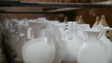 Seramik fabrikasında bir sürü kil ya da beyaz seramik vazo, sürahi ve kap kacak var. Seramik tabaklar henüz fırından çıkmamış..