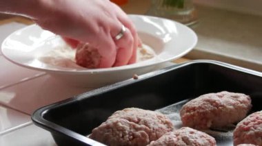 Bir kadın ev yapımı köfteler ya da kıymalı pirzola yapar, una batırır ve onları şekillendirir ve bir yemek tepsisine koyar. ev mutfağı.