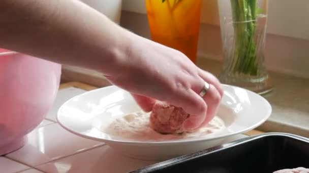 女性はミンチ肉から手作りのミートボールやカツレツを作ります 小麦粉にそれらを浸し それらを形成し ベーキングシート上に置きます 家庭用キッチン — ストック動画