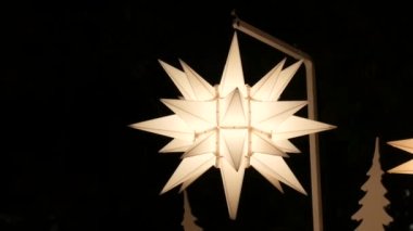 İsa 'nın doğumunun sembolü olarak karanlıkta parlayan beyaz bir Noel yıldızı şeklinde Noel süslemesi..