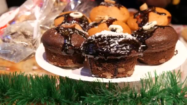 自家製フレッシュペストリー ドイツのクリスマスマーケットのカウンターでナッツや溶かしたチョコレートで飾られた大きなおいしいチョコレートカップケーキやマフィン — ストック動画