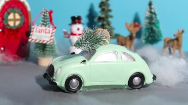 Yeni yıl ya da Noel durağı animasyonu. Çatıda Noel ağacı olan şirin bir oyuncak araba caddeden aşağı doğru gidiyor ve egzoz dumanı içiyor..