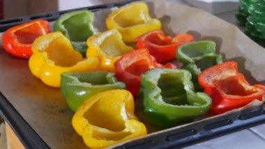 Fırında pişmiş ve buharda pişmiş sarı, kırmızı, yeşil biber baharat ve ayçiçeği yağı bir kabartma kağıdının üzerinde yatıyor.