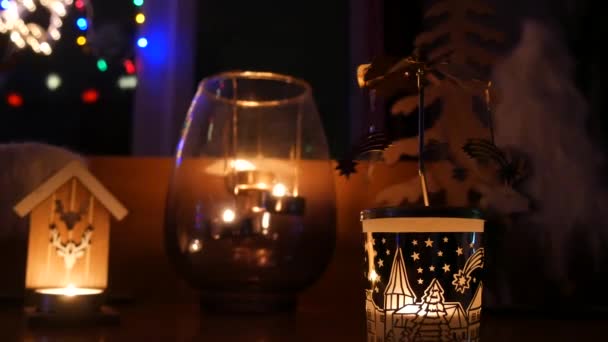 居心地の良い夜の雰囲気の中 クリスマスのキャンドルスティックは 新年のガーランドを背景に燃えるキャンドルが輝きます クリスマスと新年の雰囲気 — ストック動画