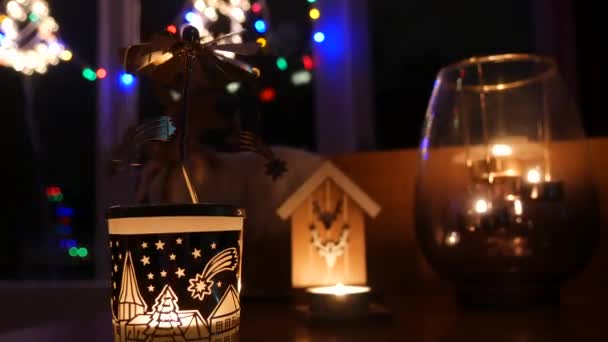 居心地の良い夜の雰囲気の中 クリスマスのキャンドルスティックは 新年のガーランドを背景に燃えるキャンドルが輝きます クリスマスと新年の雰囲気 — ストック動画