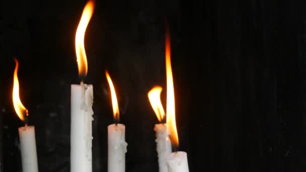 长长的白蜡教堂在黑色的背景上点燃蜡烛 祭祀用的蜡烛在庙宇里燃烧 — 图库视频影像