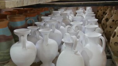 Seramik fabrikasında bir sürü kil ya da beyaz seramik vazo, sürahi ve kap kacak var. Seramik tabaklar henüz fırından çıkmamış..