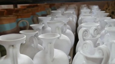 Seramik fabrikasında bir sürü kil ya da beyaz seramik vazo, sürahi ve kap kacak var. Seramik tabaklar henüz fırından çıkmamış..