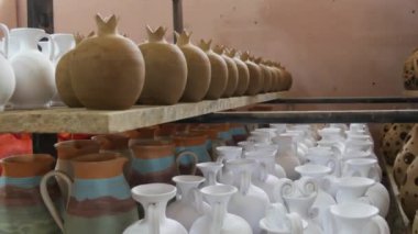 Seramik fabrikasında bir sürü kil ya da beyaz seramik vazo, sürahi ve kap kacak var. Seramik tabaklar henüz fırından çıkmamış..