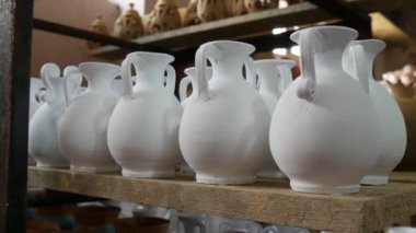 Seramik fabrikasında bir sürü kil ya da beyaz seramik vazo, sürahi ve kap kacak var. Seramik tabaklar henüz fırından çıkmamış..