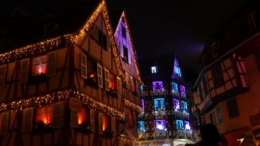 Colmar, Fransa - Aralık 2022: Noel ışıklandırması, renkli ışıklar ve çelenklerle süslenmiş güzel eski ahşap evler Alsace 'deki evin ön cephesini süslüyor.
