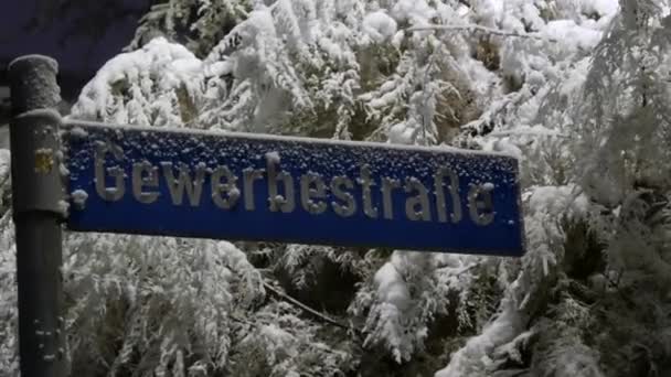 德国街道上覆盖着雪的标志 以覆盖着雪的树木和灌木丛为背景 上面有一条街道的名字 德语题词 — 图库视频影像