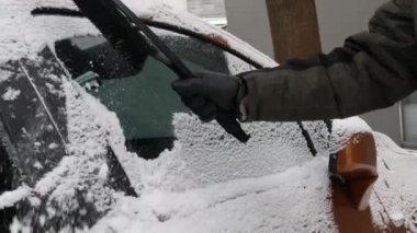 Buzla kaplı bir araba, özel bir fırçası olan bir adam arabanın yüzeyini temizler..