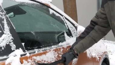 Buzla kaplı bir araba, özel bir fırçası olan bir adam arabanın yüzeyini temizler..