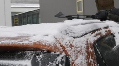 Buzla kaplı bir araba, özel bir fırçası olan bir adam arabanın yüzeyini temizler..