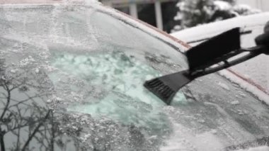 Buzla kaplı bir araba, özel bir fırçası olan bir adam arabanın yüzeyini temizler..