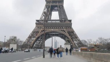 January 22, 2023 - Paris, France. Eiffel Tower in the daytime nearby, people tourists pass by.