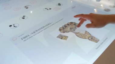 Karlsruhe, Germany - January 07, 2023: Interactive digital whiteboard table, in the history museum. A mans hand plays a game with historical finds. The latest technologies in education.