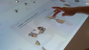 Karlsruhe, Germany - January 07, 2023: Interactive digital whiteboard table, in the history museum. A mans hand plays a game with historical finds. The latest technologies in education.