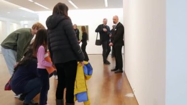BADEN-BADEN, GERMANY - FEBRUARY 2023: robot exhibition visitors look in surprise at a cute talking white mouse.