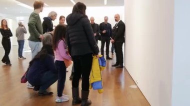 BADEN-BADEN, GERMANY - FEBRUARY 2023: robot exhibition visitors look in surprise at a cute talking white mouse.