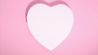 Stop motion animation of hearts. Copy space. Concept of love, Valentines Day. Many small red hearts move around big white heart on pink background. Greeting love video. Symbol of love. Template text.