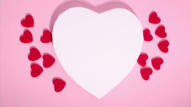 Stop motion animation of hearts. Copy space. Concept of love, Valentines Day. Many small red hearts move around big white heart on pink background. Greeting love video. Symbol of love. Template text.