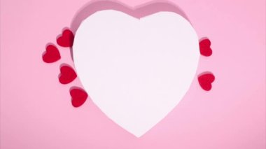 Stop motion animation of hearts. Copy space. Concept of love, Valentines Day. Many small red hearts move around big white heart on pink background. Greeting love video. Symbol of love. Template text.