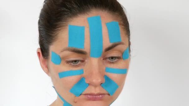 Mujer Joven Aplica Tiras Kinesio Azul Claro Que Pegan Cara — Vídeo de stock