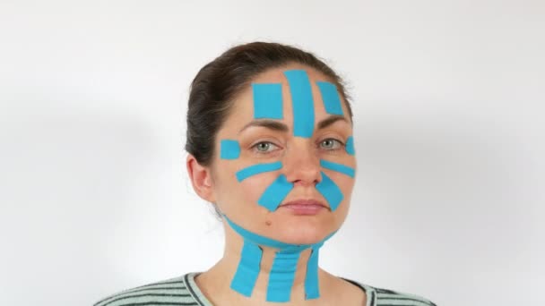Mujer Joven Aplica Tiras Kinesio Azul Claro Que Pegan Cara — Vídeos de Stock