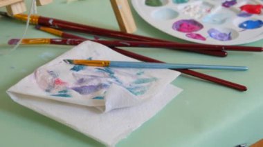 Çizim işlemi. Bir palette çeşitli resimler, bir sanat stüdyosunda bir masanın üzerinde fırçalar..