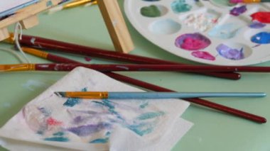 Çizim işlemi. Bir palette çeşitli resimler, bir sanat stüdyosunda bir masanın üzerinde fırçalar..