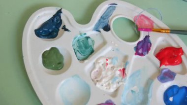 Çizim işlemi. Bir palette çeşitli resimler, bir sanat stüdyosunda bir masanın üzerinde fırçalar..
