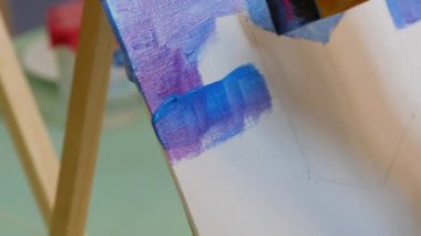 Çizim dersleri. Sanatçının biri stüdyoda fırçayla tuvale resim çiziyor..