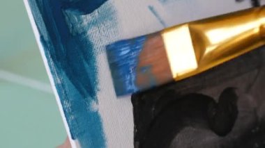 Çizim dersleri. Sanatçının biri stüdyoda fırçayla tuvale resim çiziyor..