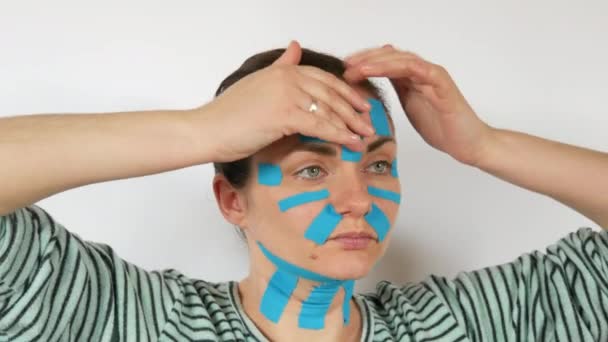 Ung Kvinna Applicerade Ljusblå Kinsio Remsor Tejpa Ansikte Panna Hals — Stockvideo