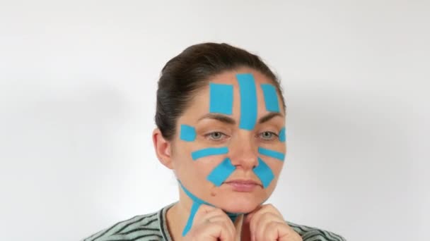 Mujer Joven Aplica Tiras Kinesio Azul Claro Que Pegan Cara — Vídeo de stock